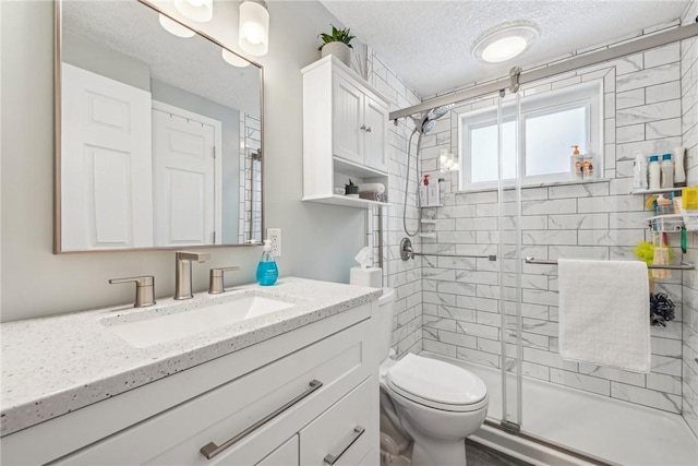 bathroom with a textured ceiling, toilet, vanity, and an enclosed shower