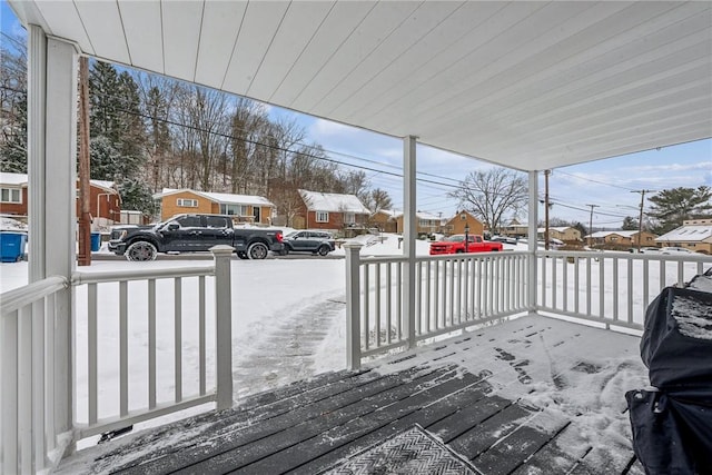 snow covered deck featuring covered porch and a grill