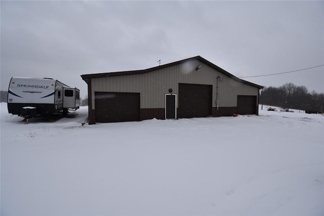 snow covered structure featuring a garage