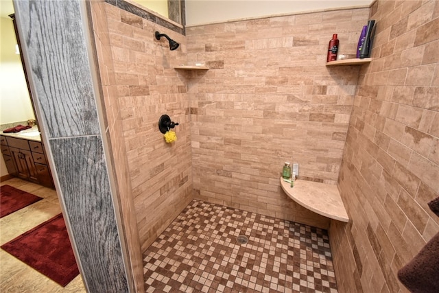 bathroom with tiled shower and vanity