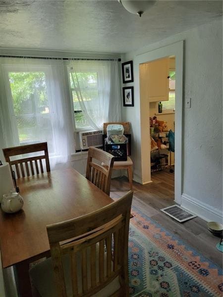 dining room with plenty of natural light, wood-type flooring, a textured ceiling, and cooling unit