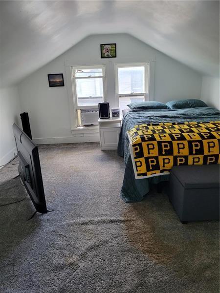 bedroom featuring dark carpet, lofted ceiling, and cooling unit