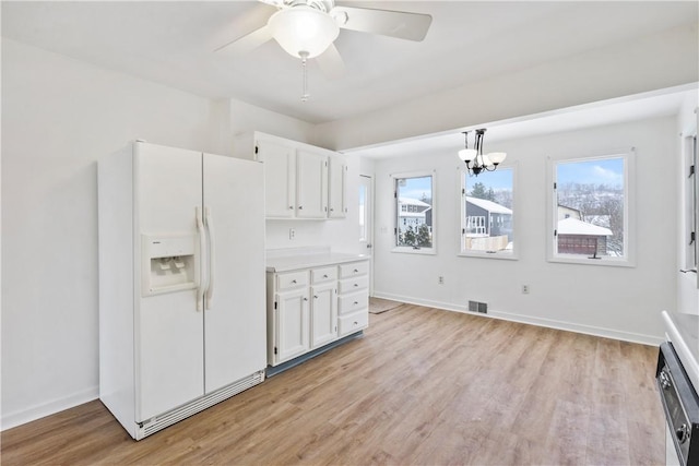 kitchen featuring decorative light fixtures, plenty of natural light, white cabinetry, and white refrigerator with ice dispenser