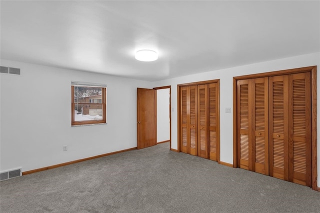 unfurnished bedroom with multiple closets and carpet flooring