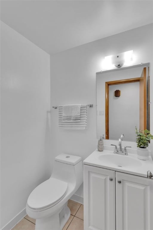 bathroom with toilet, vanity, and tile patterned flooring