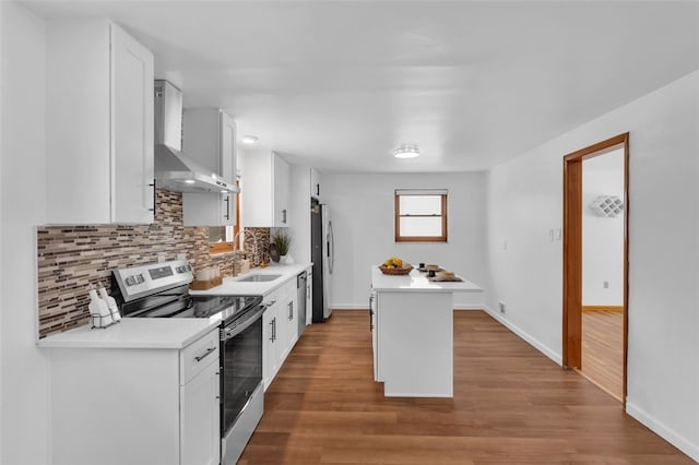 kitchen with stainless steel appliances, sink, white cabinetry, and wall chimney range hood