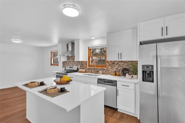 kitchen featuring a center island, wall chimney exhaust hood, white cabinetry, stainless steel appliances, and sink