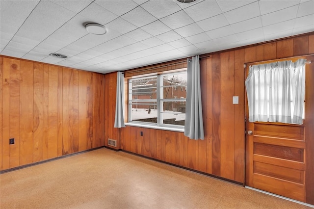 unfurnished room featuring a healthy amount of sunlight and wooden walls