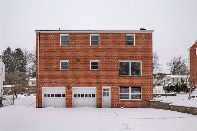 snow covered house featuring a garage