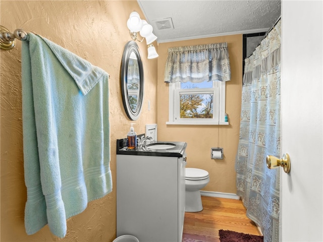 bathroom featuring hardwood / wood-style floors, a textured ceiling, vanity, toilet, and crown molding