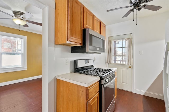 kitchen featuring ceiling fan, dark hardwood / wood-style flooring, crown molding, and stainless steel appliances