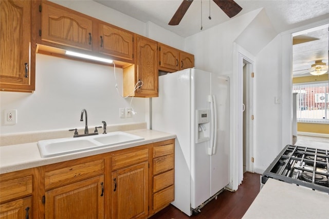 kitchen featuring ceiling fan, gas range, white fridge with ice dispenser, and sink