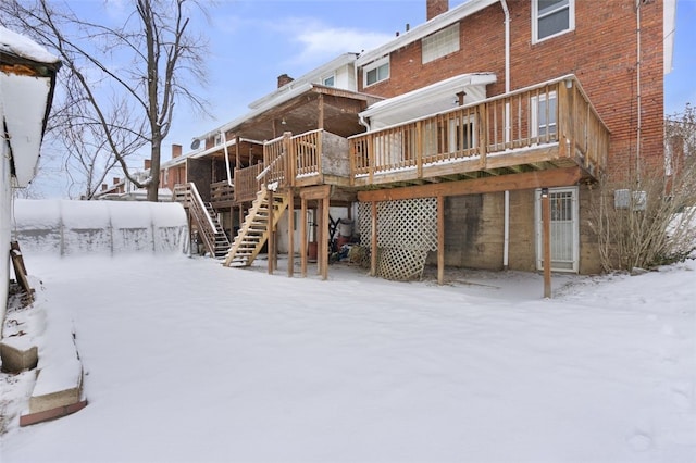 snow covered back of property with a deck