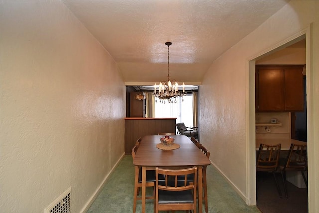 carpeted dining room featuring a textured ceiling and an inviting chandelier