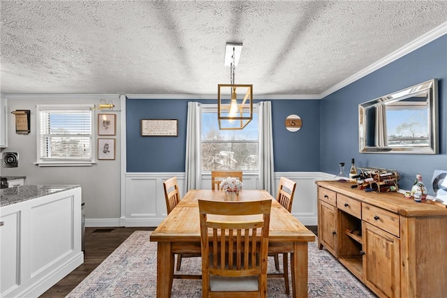 dining space with a chandelier, dark wood-type flooring, ornamental molding, and a textured ceiling