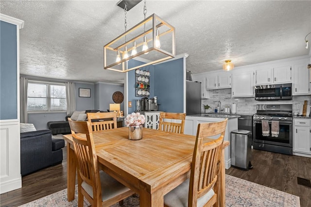 dining space with dark wood-type flooring, a textured ceiling, sink, and crown molding