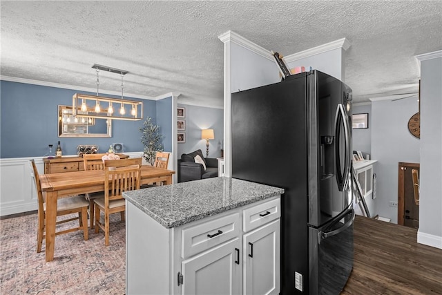 kitchen featuring hanging light fixtures, white cabinets, black fridge, and ornamental molding