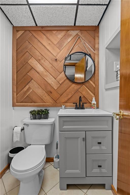 bathroom with toilet, wooden walls, tile patterned floors, and vanity