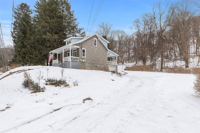 snow covered property with covered porch