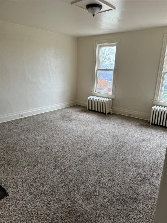 carpeted spare room featuring radiator heating unit