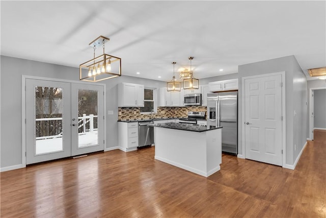 kitchen with appliances with stainless steel finishes, white cabinets, hanging light fixtures, and a kitchen island