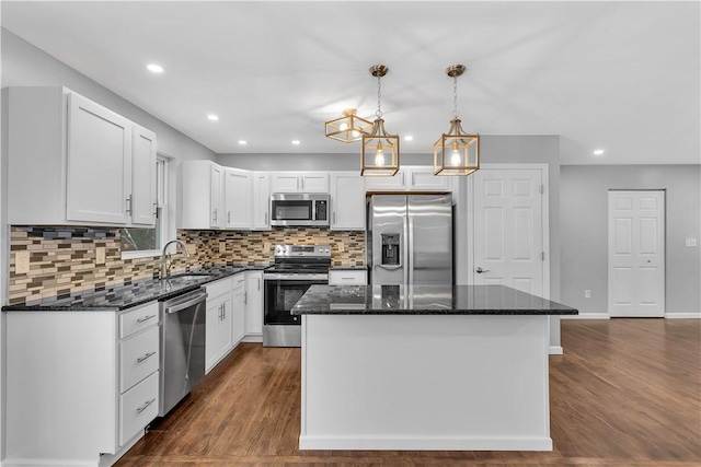 kitchen featuring appliances with stainless steel finishes, white cabinetry, decorative light fixtures, and a center island