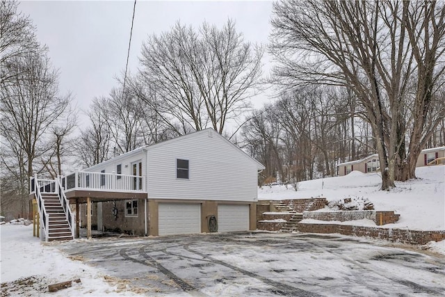 snow covered property featuring a wooden deck and a garage