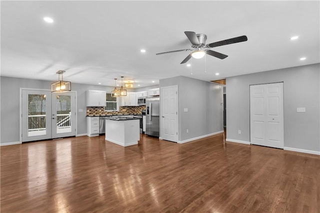 unfurnished living room featuring ceiling fan with notable chandelier and dark hardwood / wood-style flooring