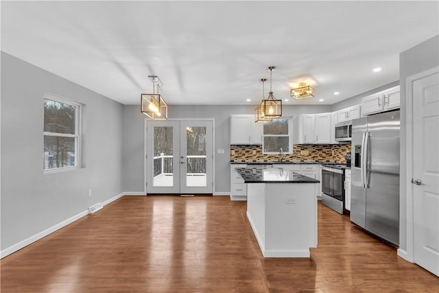 kitchen featuring stainless steel appliances, white cabinetry, and decorative light fixtures