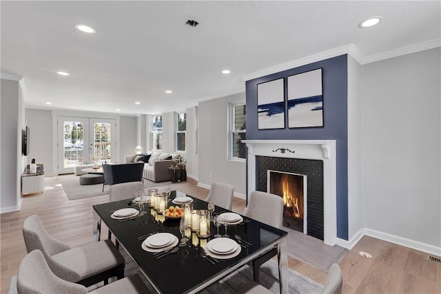 dining room featuring a tile fireplace, ornamental molding, and light hardwood / wood-style floors