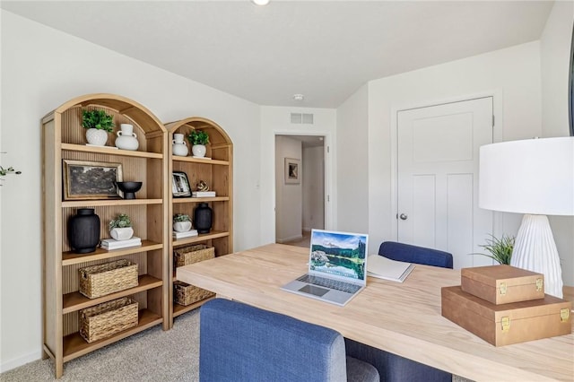 office space with light colored carpet and built in shelves