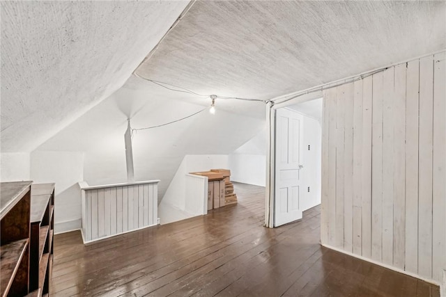 bonus room featuring vaulted ceiling, dark hardwood / wood-style flooring, and wooden walls