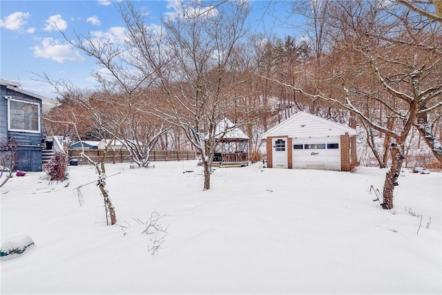 snowy yard with an outbuilding, a gazebo, and a garage