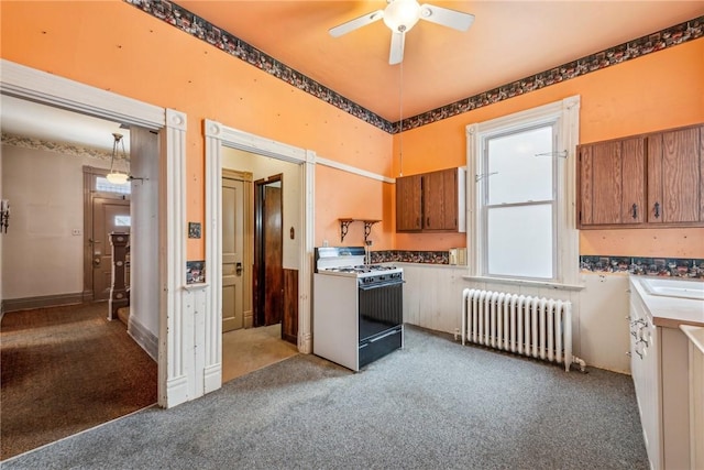 kitchen with light carpet, ceiling fan, decorative light fixtures, white gas stove, and radiator heating unit