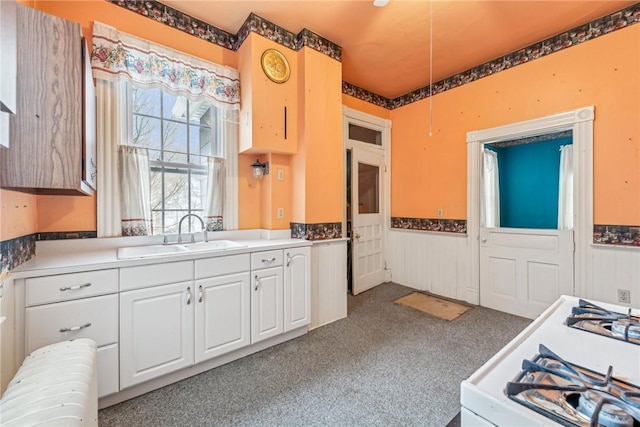 kitchen with white cabinets, sink, white gas stove, and dark carpet