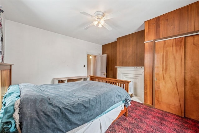 carpeted bedroom featuring ceiling fan, a closet, and wooden walls