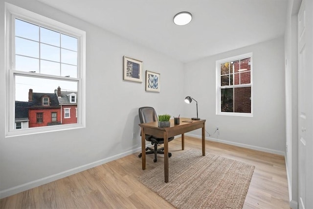 office with light wood-type flooring and a wealth of natural light