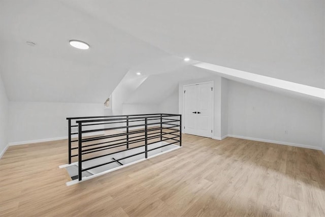 bonus room with light wood-type flooring and lofted ceiling