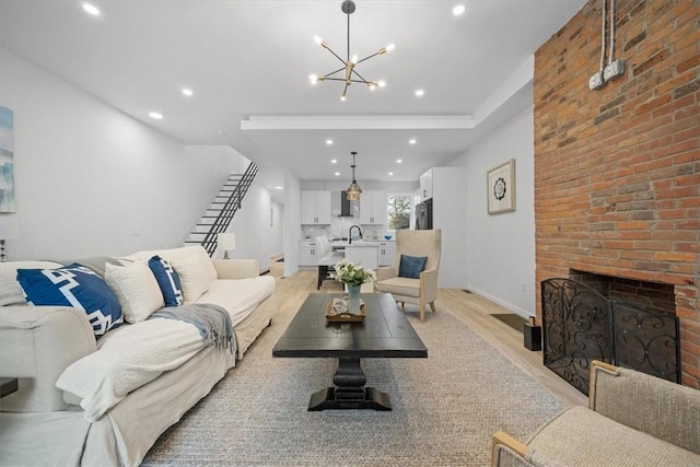 living room with a brick fireplace, light hardwood / wood-style flooring, and an inviting chandelier