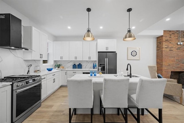 kitchen featuring tasteful backsplash, a kitchen island with sink, wall chimney exhaust hood, and stainless steel appliances