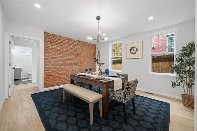 dining space with light hardwood / wood-style flooring and an inviting chandelier