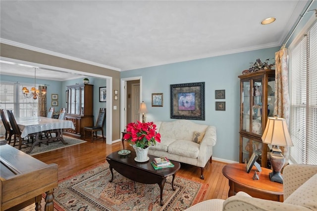 living room featuring a wealth of natural light, hardwood / wood-style floors, crown molding, and a notable chandelier