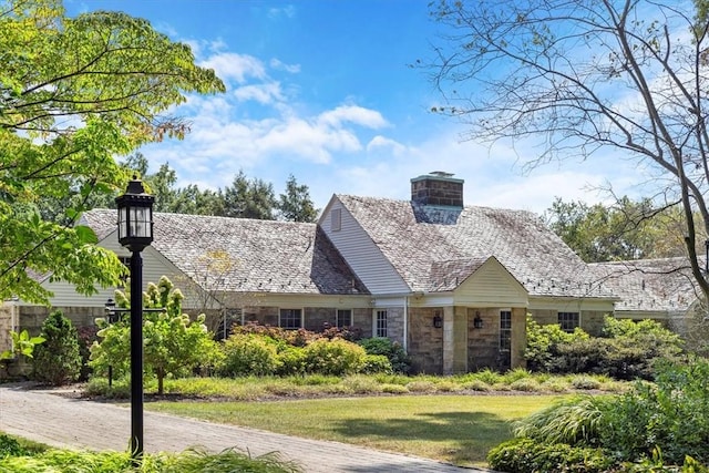 view of front facade featuring stone siding, a high end roof, and a front lawn