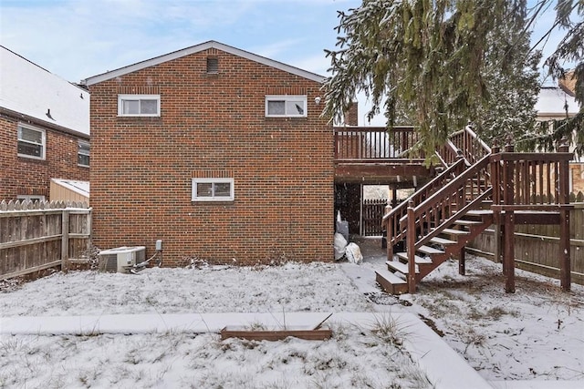 snow covered rear of property featuring a deck and central AC