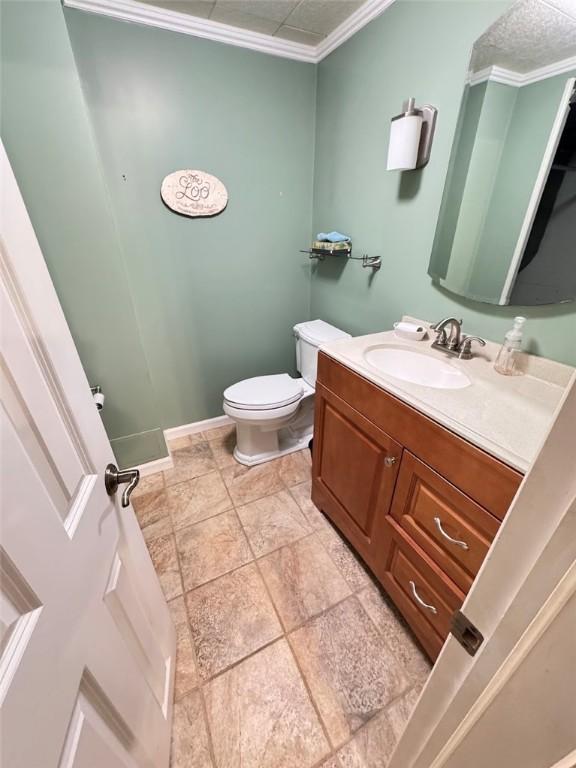 bathroom with toilet, ornamental molding, and vanity