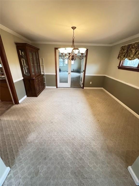 unfurnished dining area with carpet floors, a notable chandelier, and crown molding