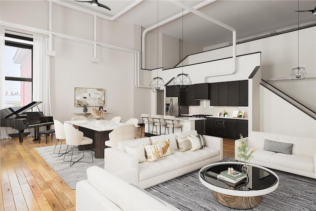 living room with ceiling fan, a towering ceiling, and light wood-type flooring