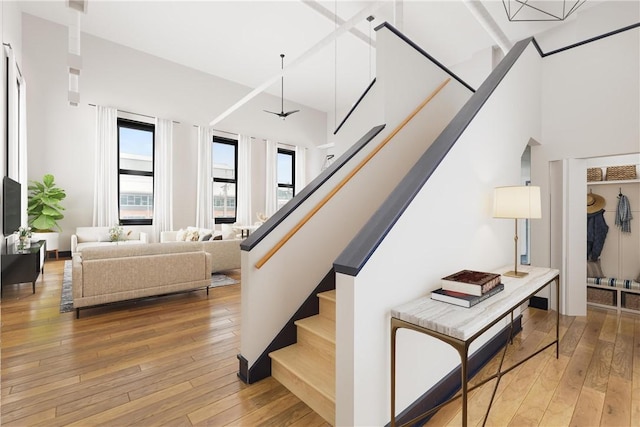 stairs featuring ceiling fan, a towering ceiling, and hardwood / wood-style floors