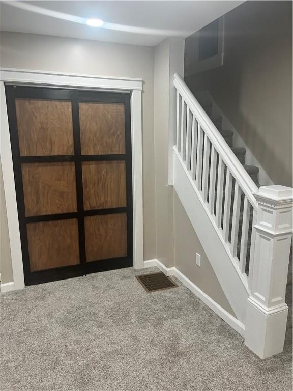 entryway featuring carpet, baseboards, and stairway