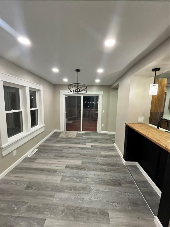 unfurnished dining area featuring wood finished floors, a chandelier, baseboards, and recessed lighting